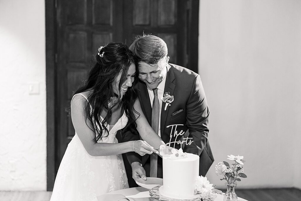 Bride and groom bend over to cut their wedding cake