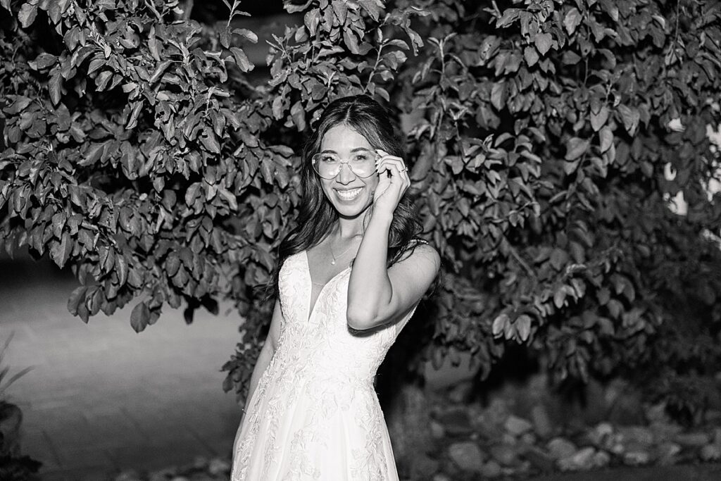 Black and white photo of bride leaning over and touching her heart shaped glsses