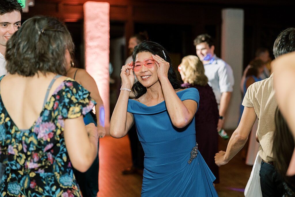 Woman in blue dress holding sunglasses while dancing