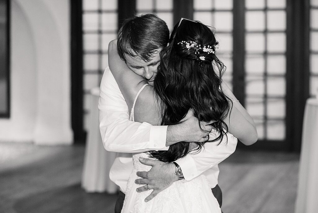 Black and white photo of groom hugging bride