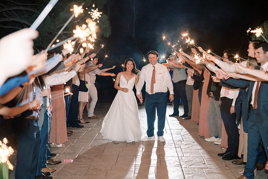 Bride and groom walking arm in arm through sparklers after their wedding