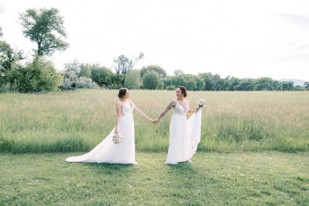 Bride leading another bride across a field