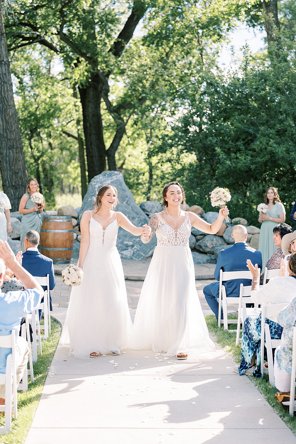 Two women walking down the aisle with their hands in the air after wedding ceremony