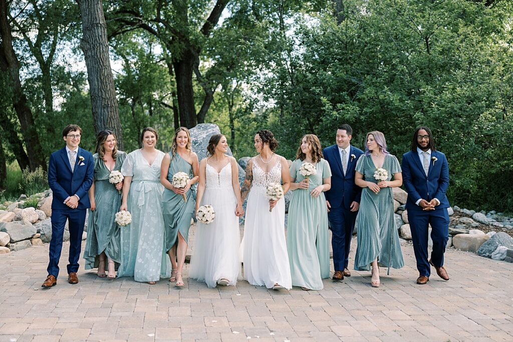 Two brides walking with their wedding party in blue dresses and blue suits