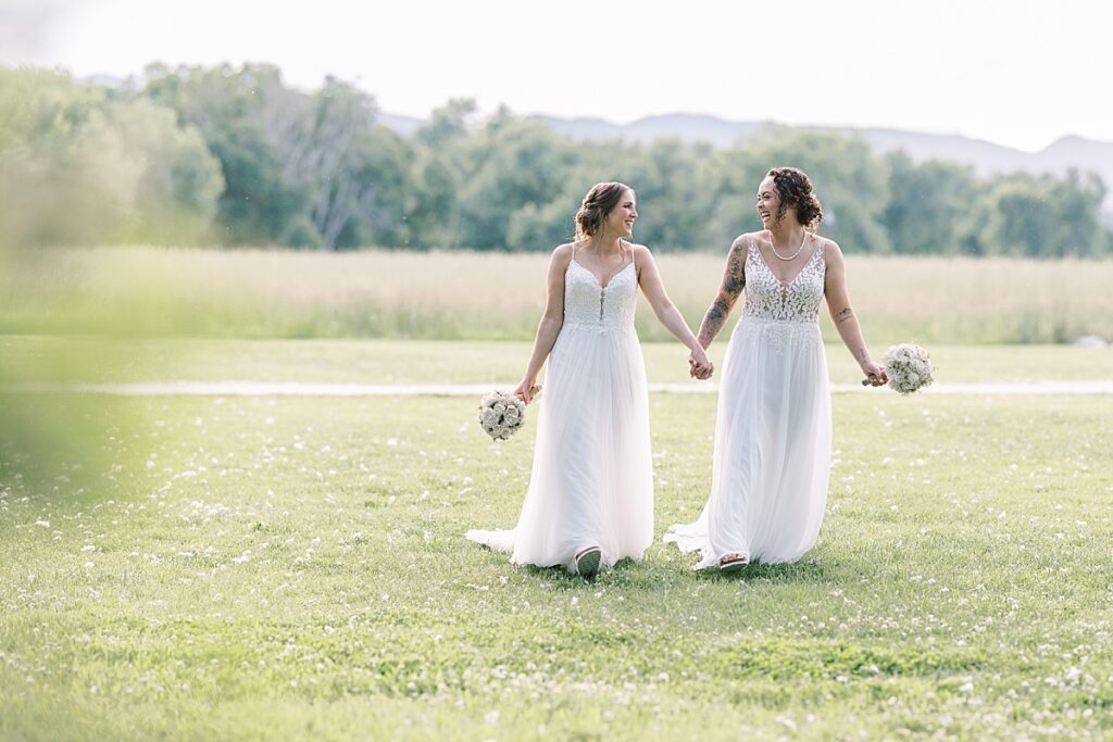 Two brides holding hands and walking towards camera