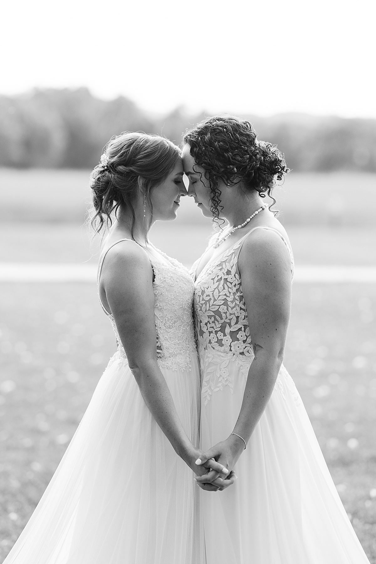 Black and white photo of two brides standing forehead to forehead