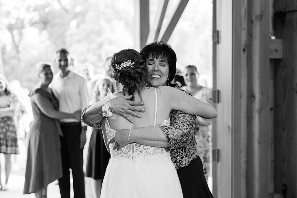 Woman with dark hair hugging bride after dance