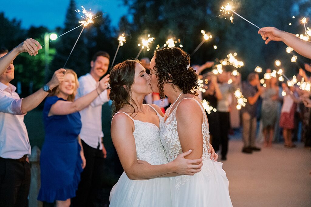 Two women kissing with sparklers in the background