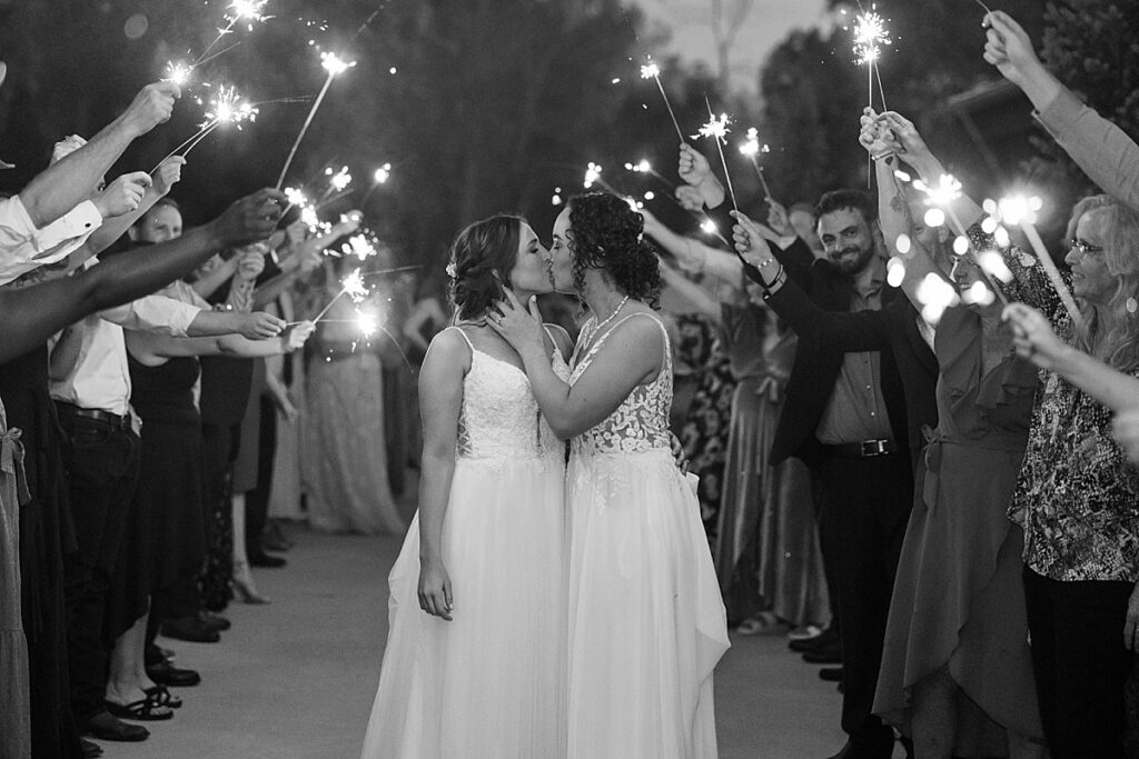 Black and white photo of couple standing in front of sparklers kissing