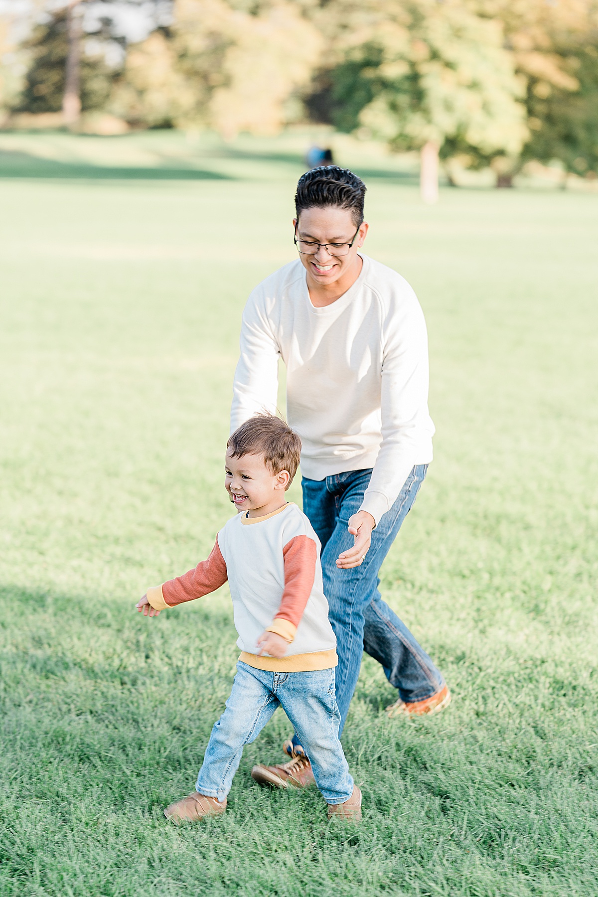 Man in white sweater and young boy running around in a field