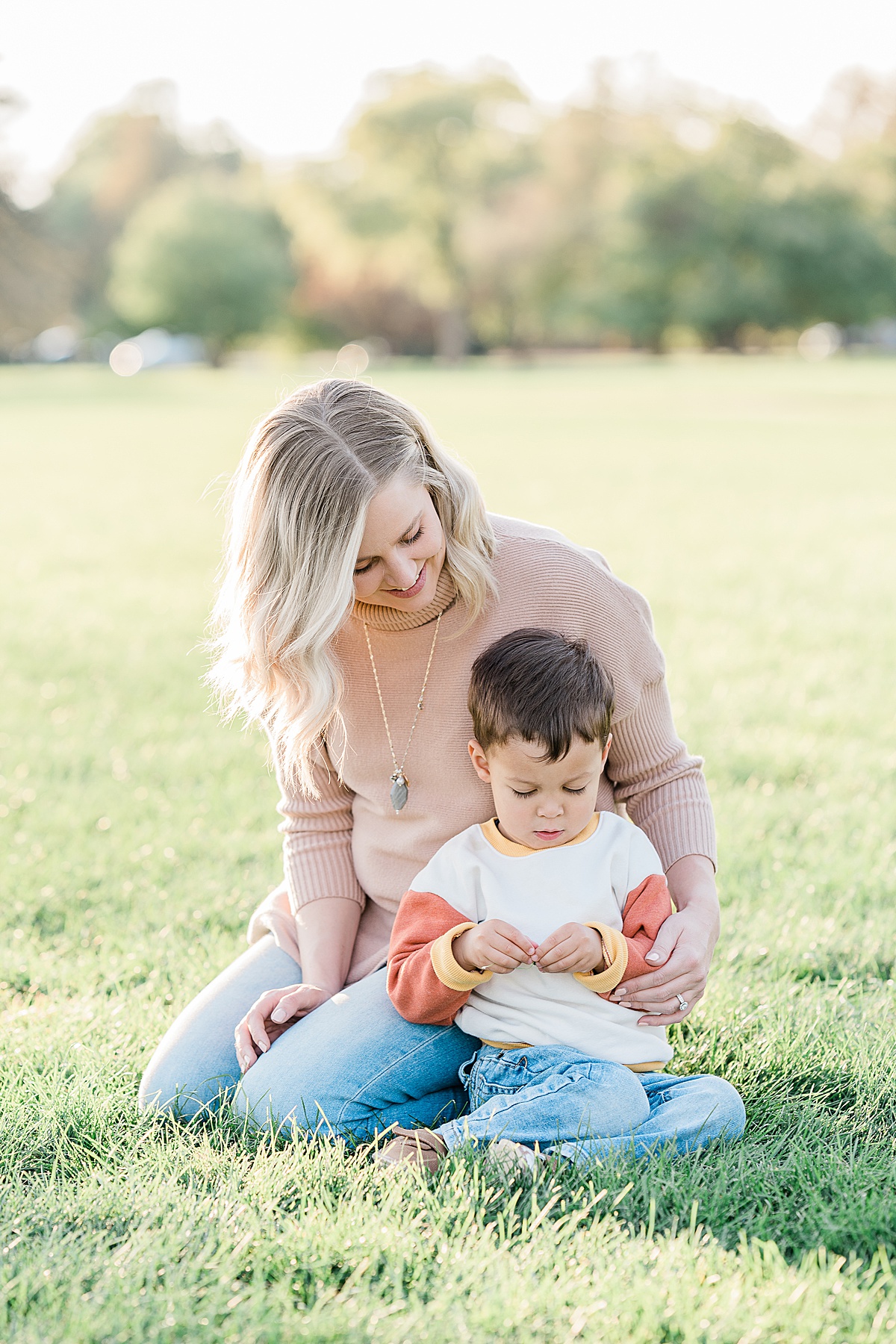 Woman in pink sweater kneeling on ground with small boy