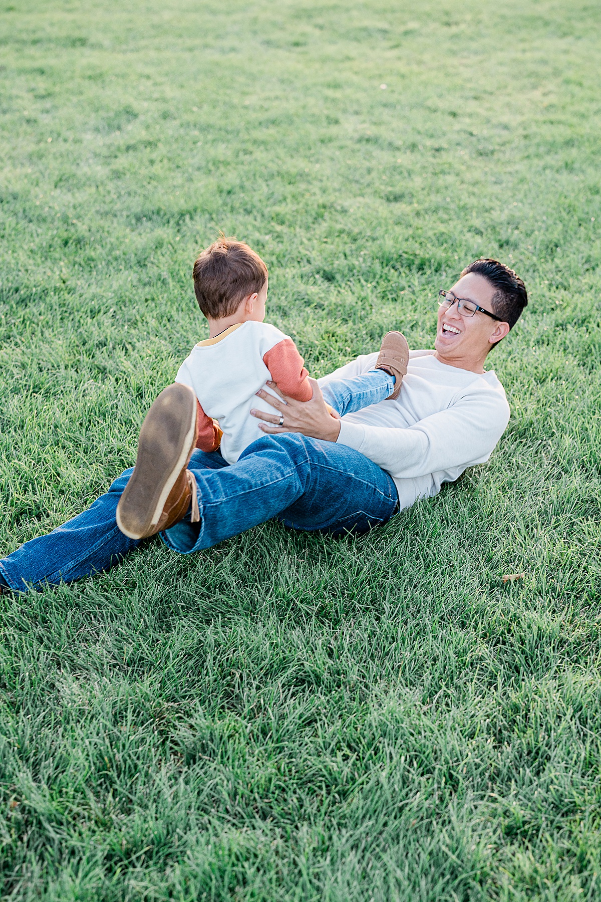 Boy in blue jeans and white and orange sweater wrestling with man in glasses