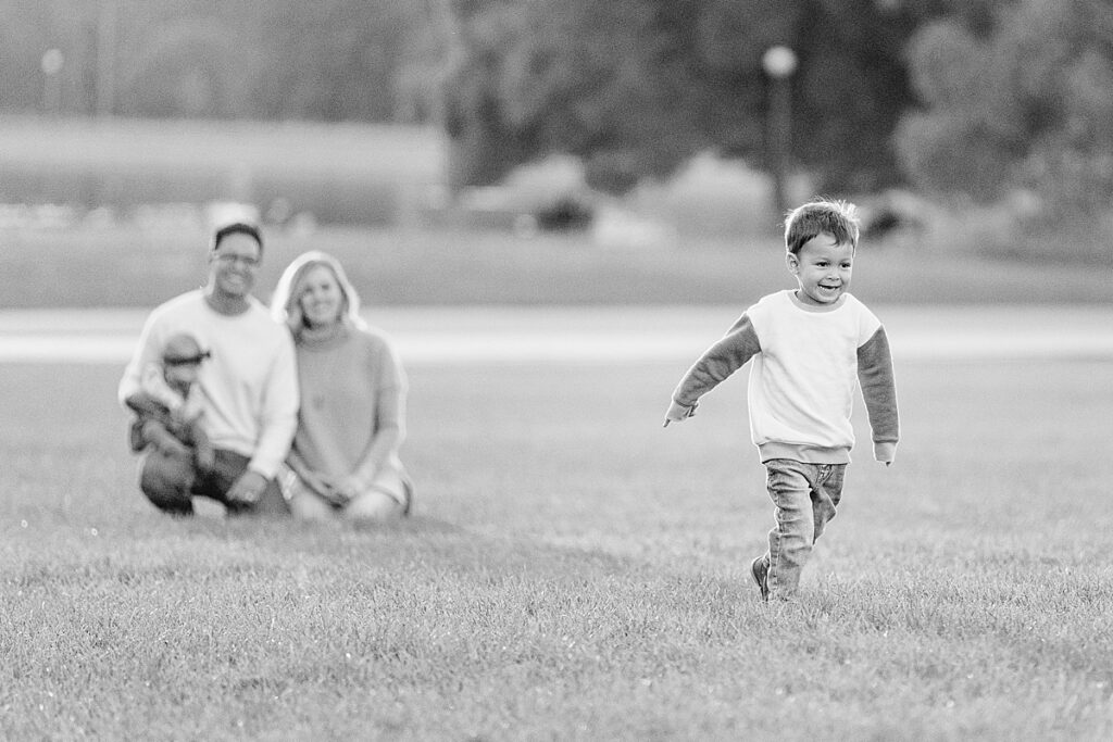 Black and white photo of young boy running away from man and woman in background