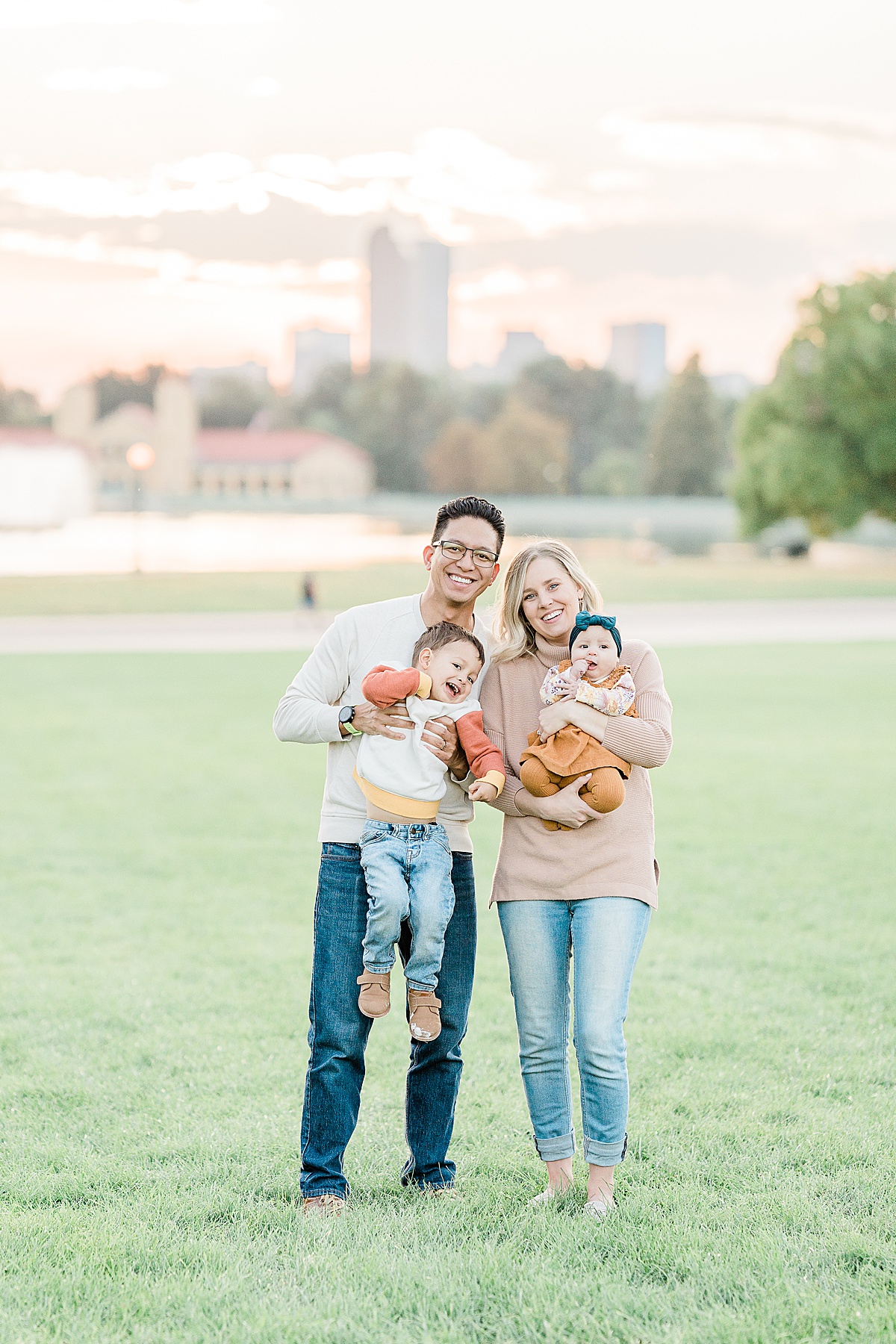 Woman in pink sweater and man in white sweater posing with small boy and baby girl