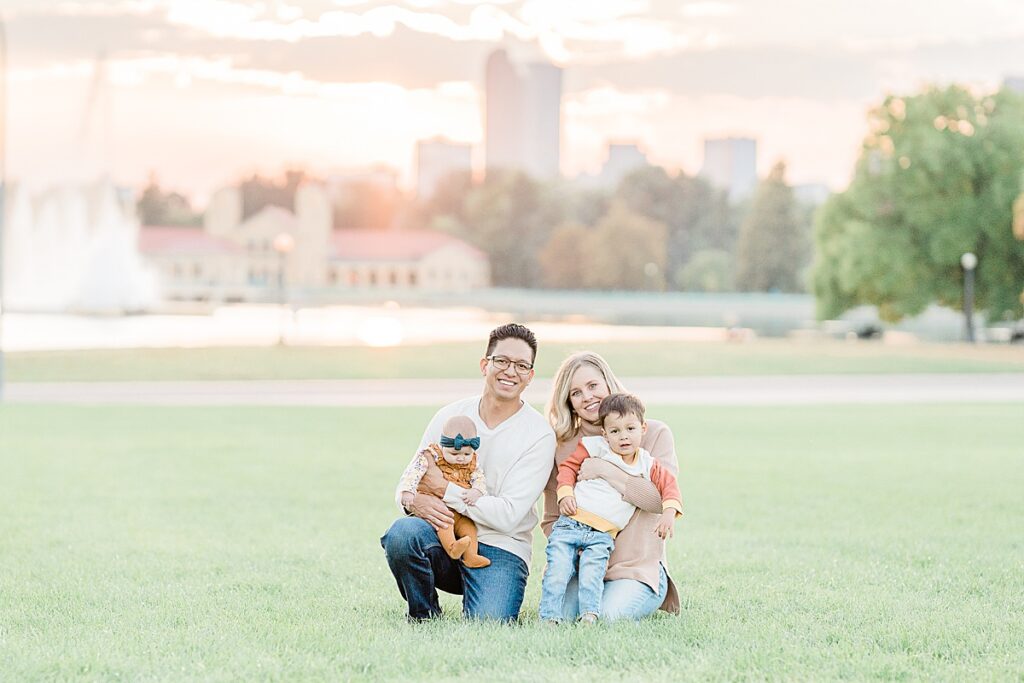 Man and woman kneeling down on grass holding young boy and baby girl