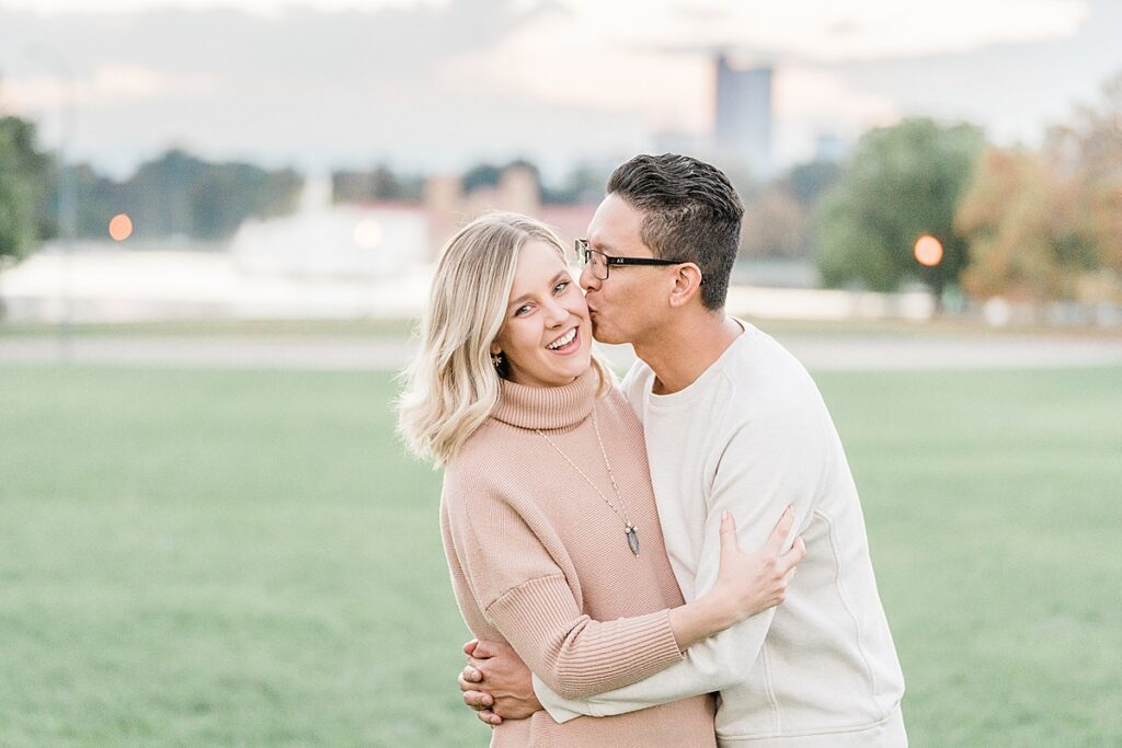 Man in white sweater with dark hair kissing woman with blond hair on the cheek