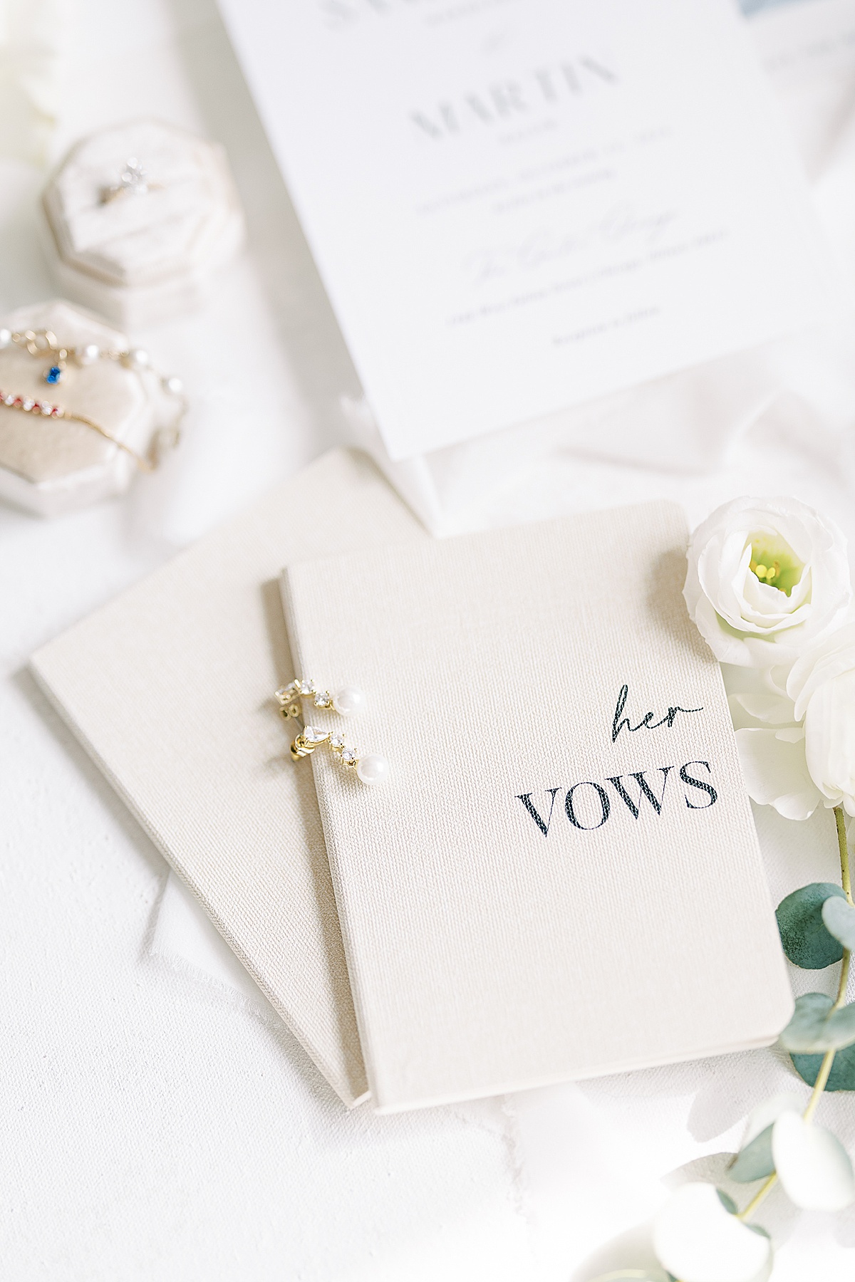 White vow books with pearl earrings on top