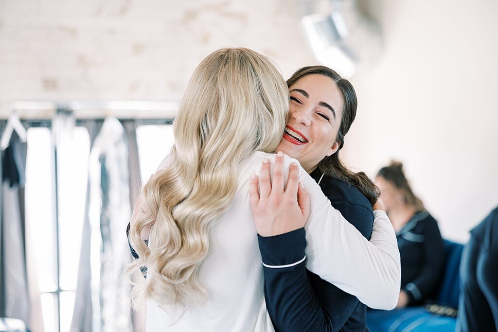 Bride hugging bridesmaid in black outfit