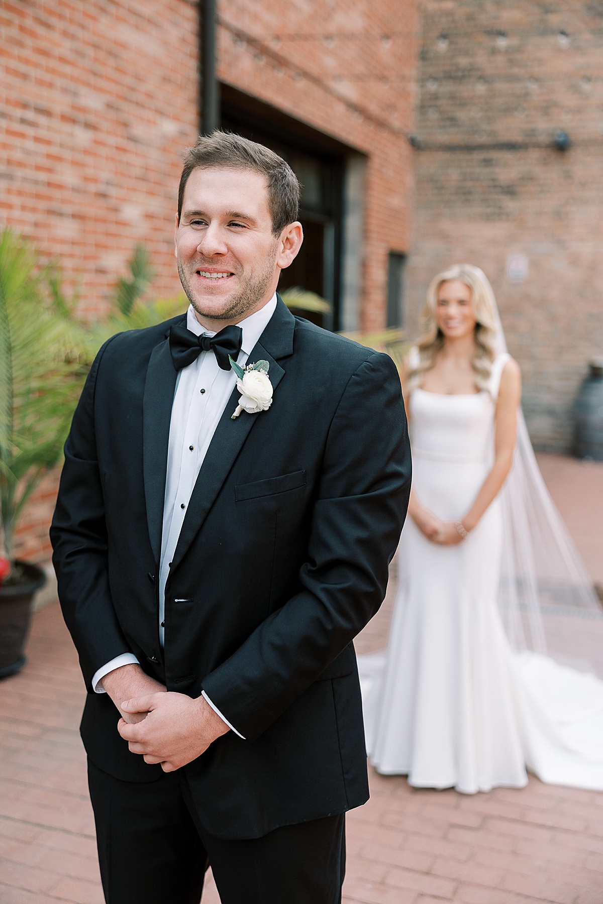 Groom smiling with bride behind him