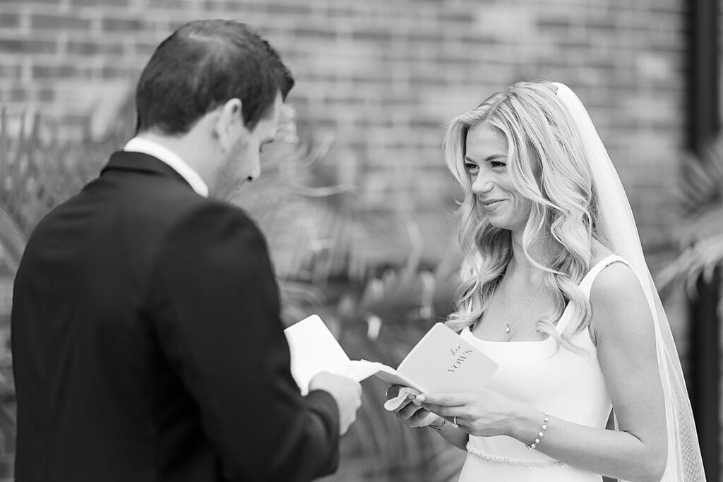 Black and white image of bride and groom reading vows