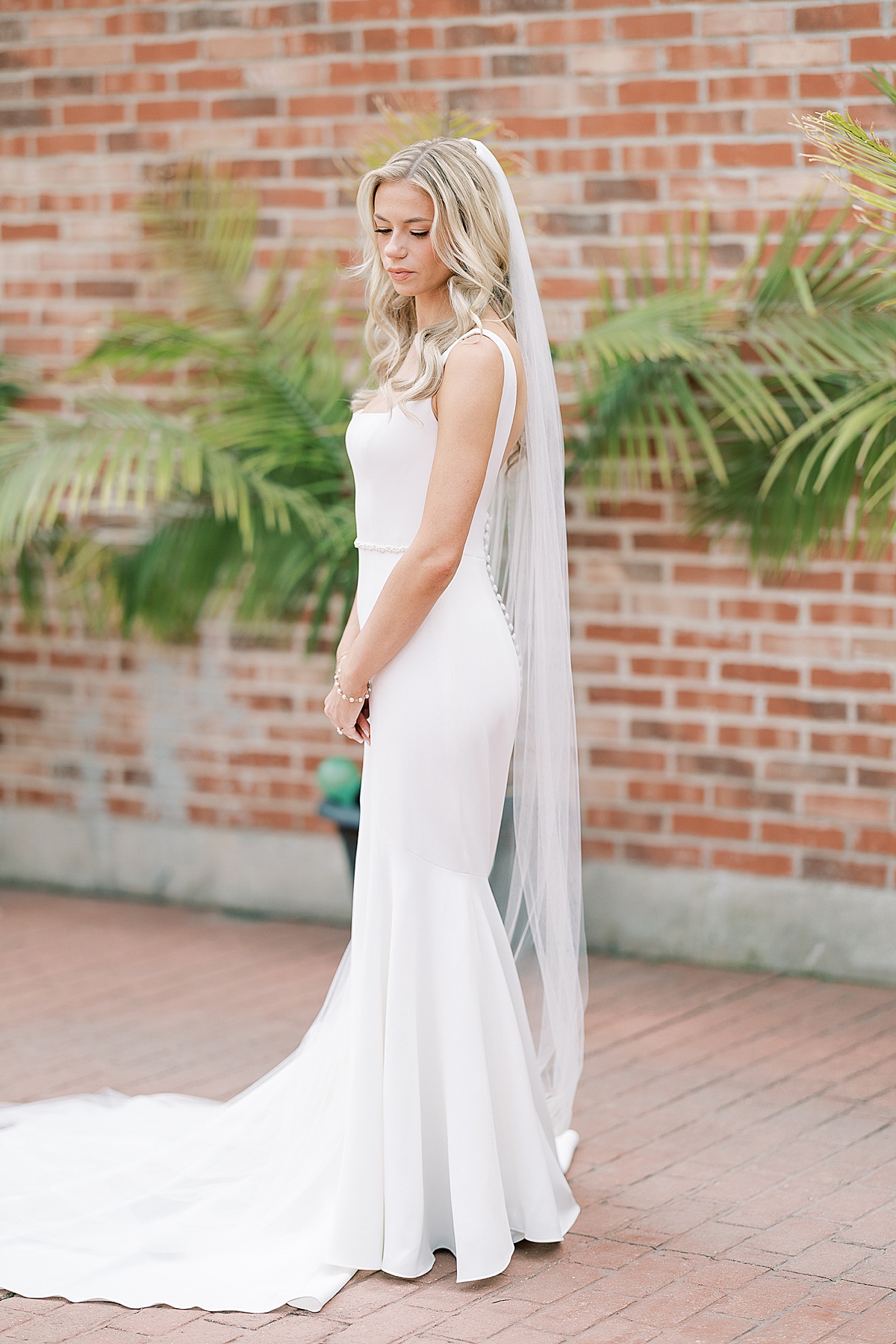 Bride looking down at floor with white dress and veil