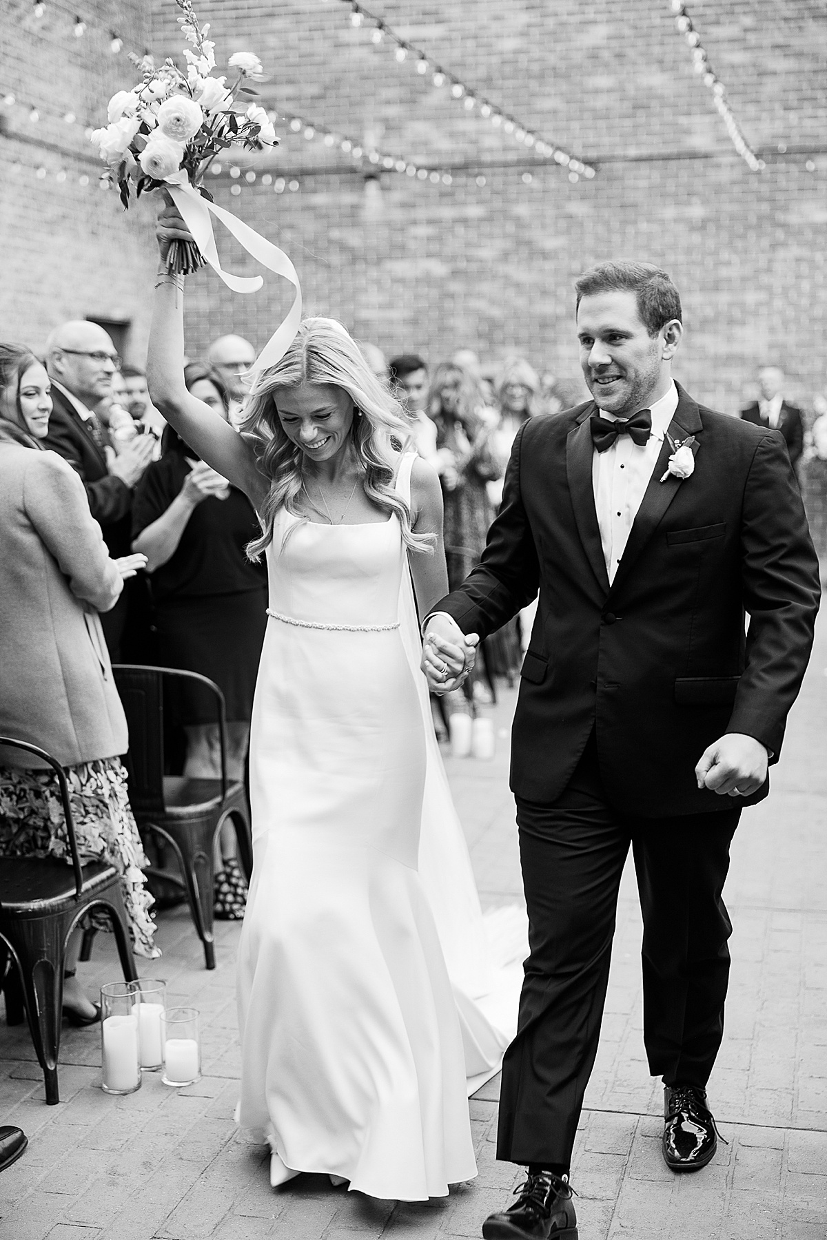 Black and white photo of couple walking away from wedding ceremony