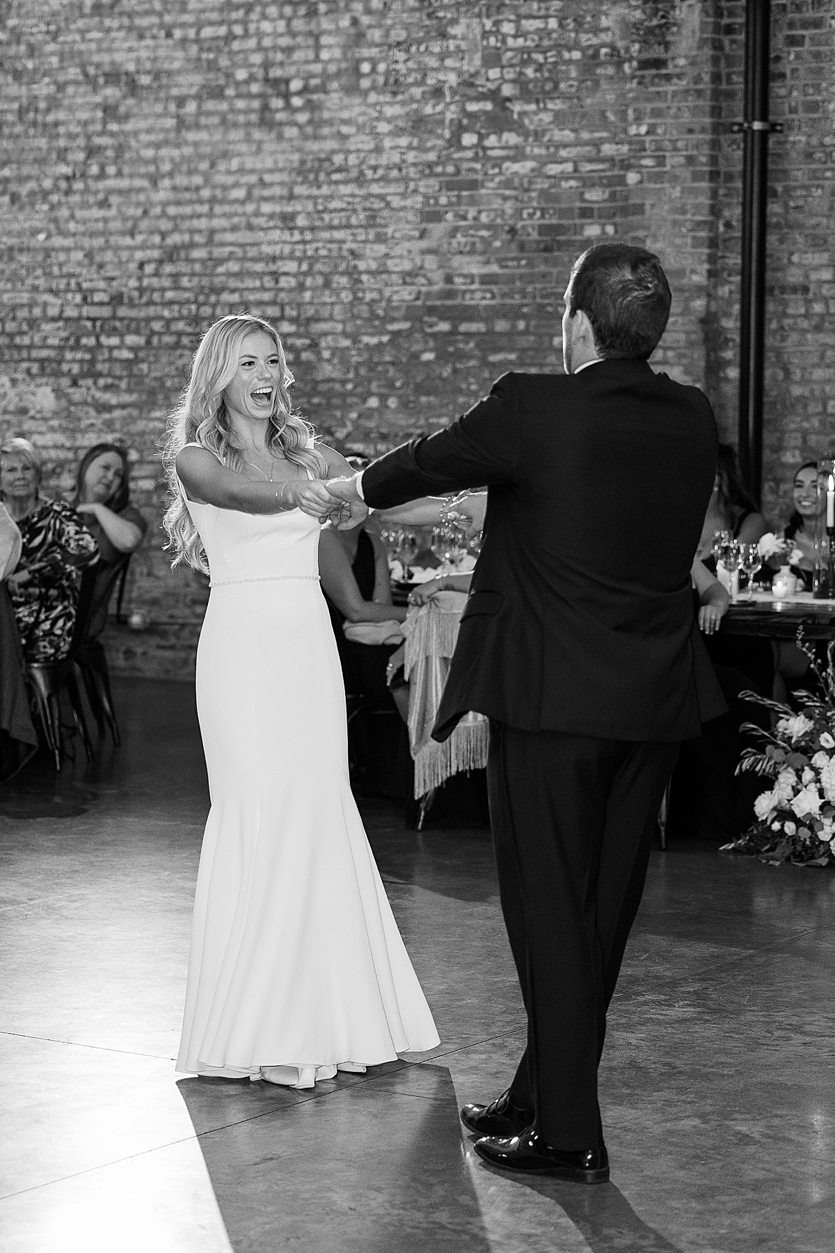 Bride smiles at groom while dancing