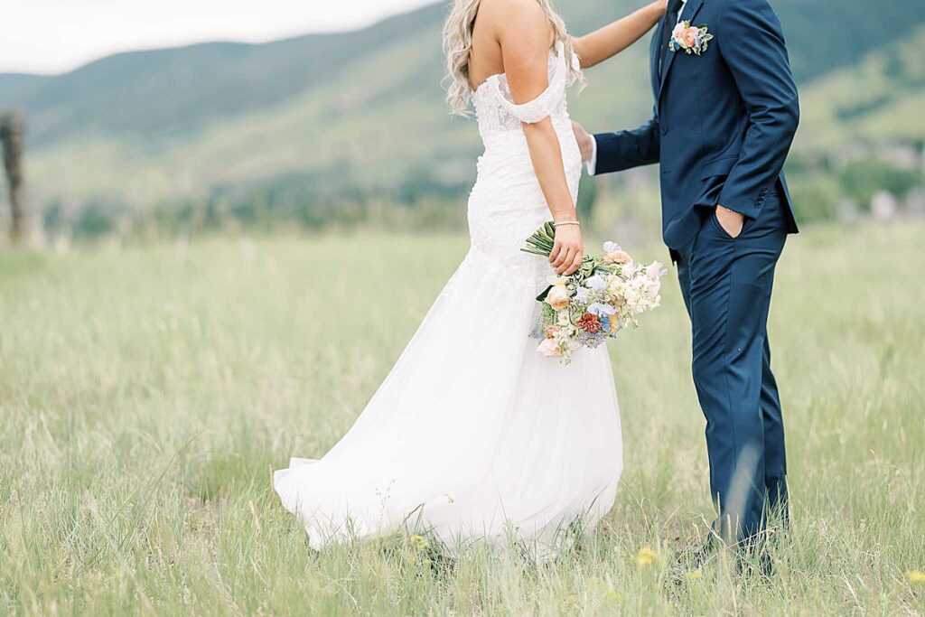 Couple standing in field holding flowers