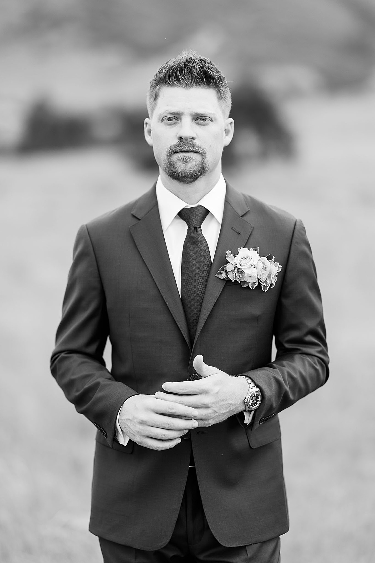 Black and white photo of groom looking at camera playing with wedding ring