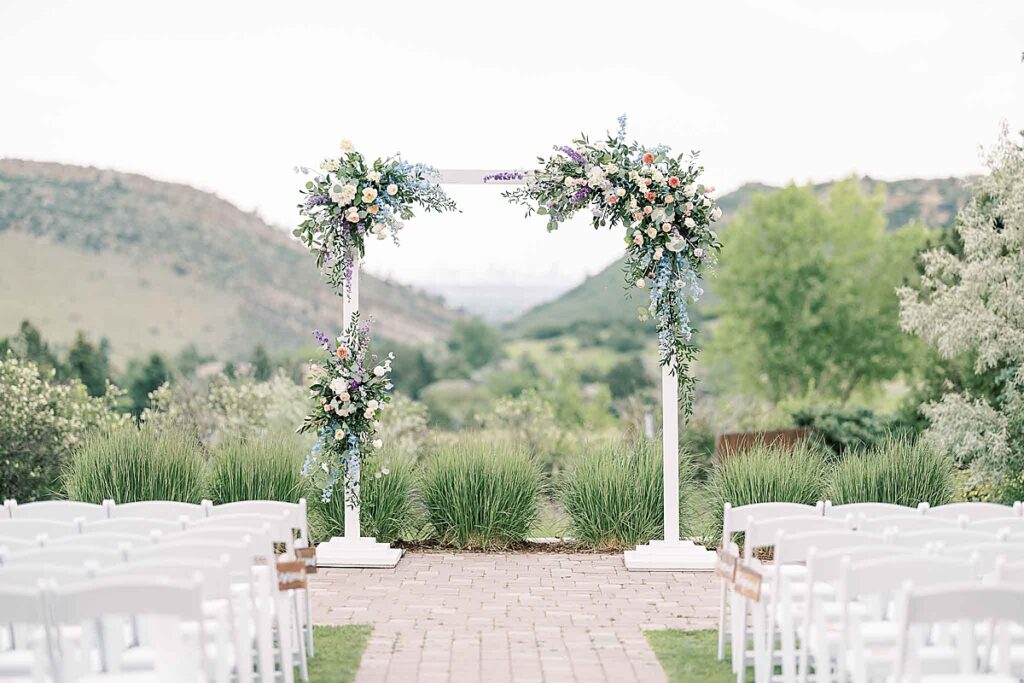 Floral arch in front of white ceremony chairs