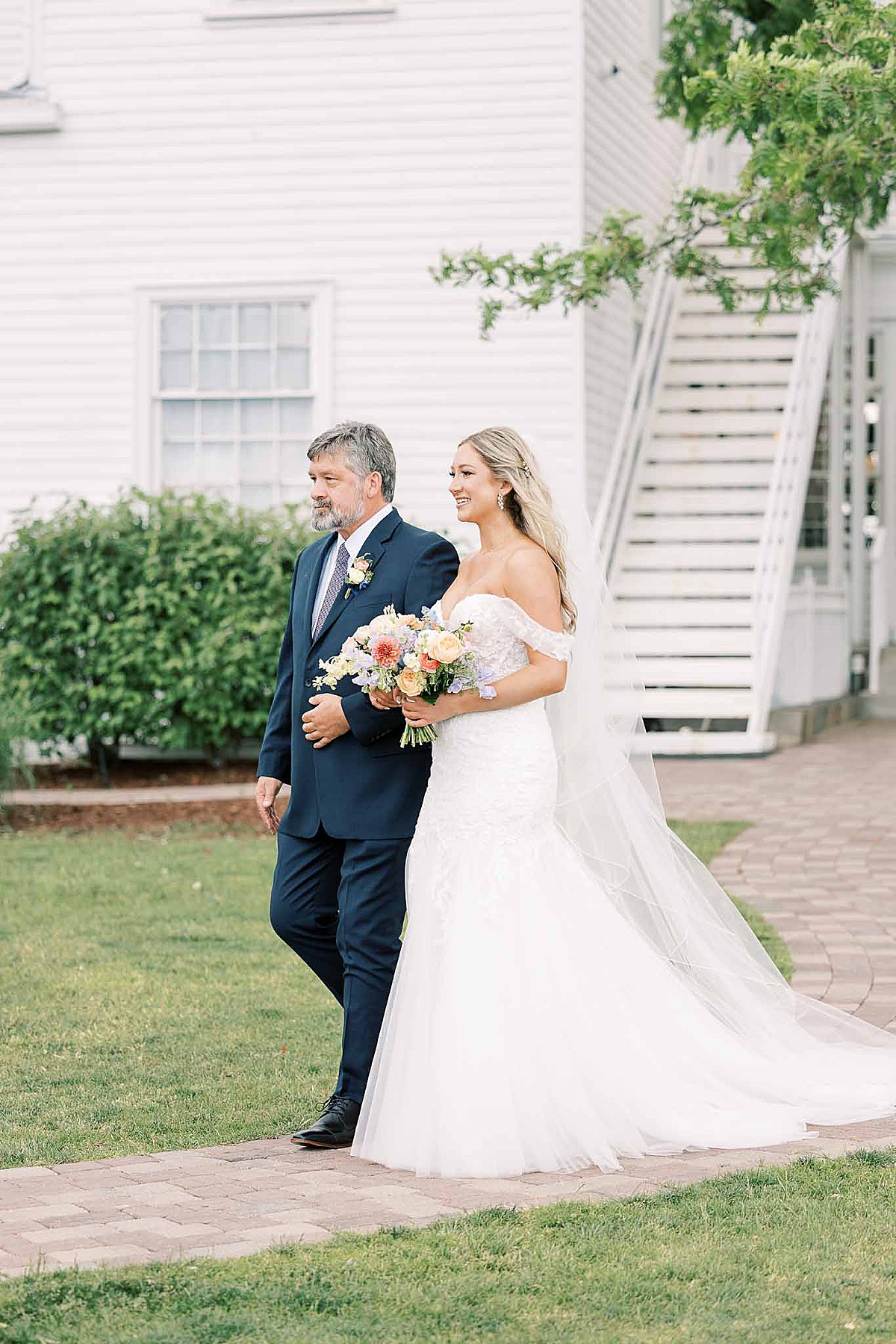 Father walking bride in white dress down aisle