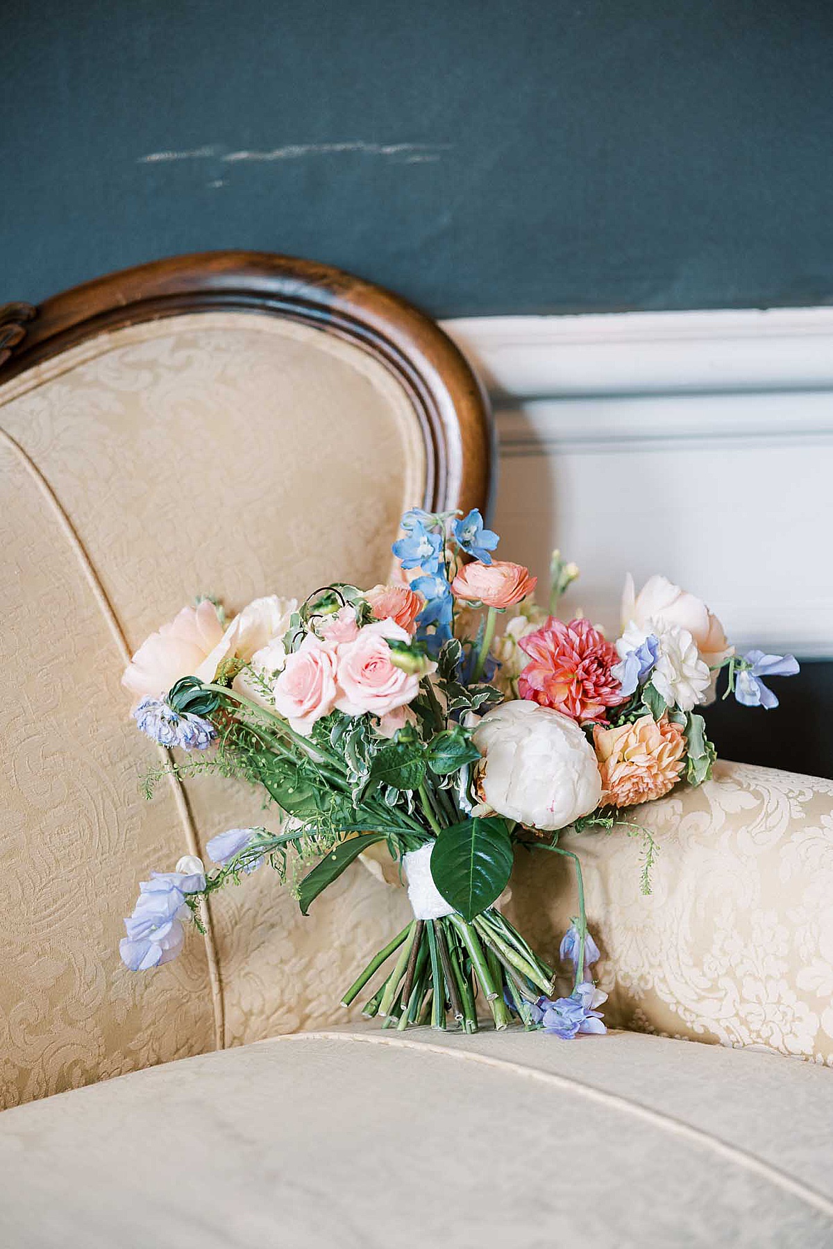 Wedding bouquet sitting on tan bench in front of black wall