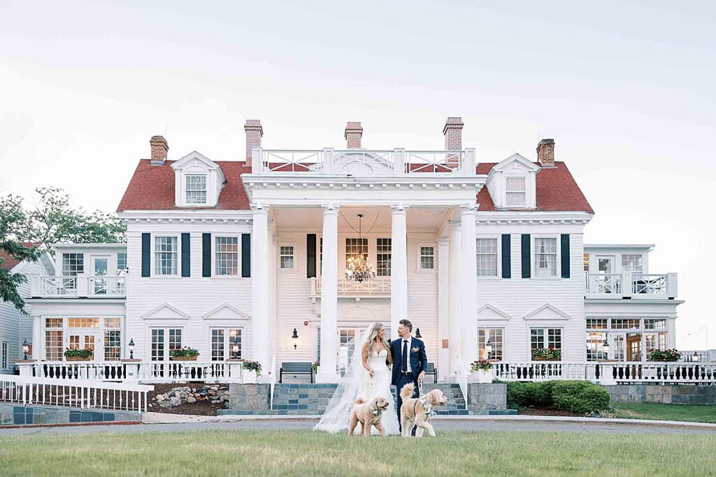 Bride and groom walking in front of Manor House Colorado with two dogs