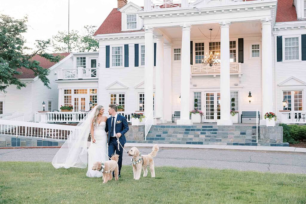 Bride and groom walking with their dogs outside Manor House